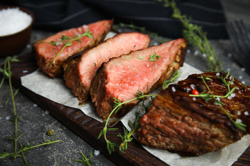 Board with slices of grilled meat on grey table, closeup