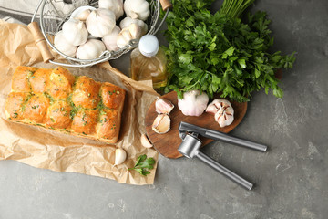 Buns of bread with garlic and herbs on grey table, flat lay