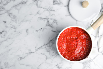 Delicious tomato sauce in pan on marble table, top view. Space for text