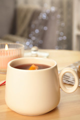 Cup of hot mulled wine on wooden table indoors. Winter drink