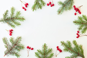 Fototapeta na wymiar Flat lay christmas frame with evergreen tree branch and berries on a white background