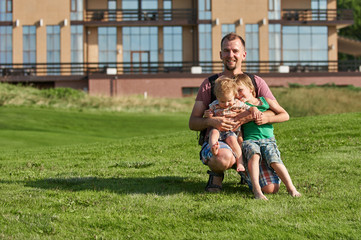 happy young father holding two sons in the park