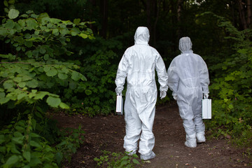 Naklejka na ściany i meble Ecological problem. Pollution. Examine soil. Scientist working in forest in protective mask and suit taking water and soil samples. Chemist makes an analysis of the environment for radiation. 