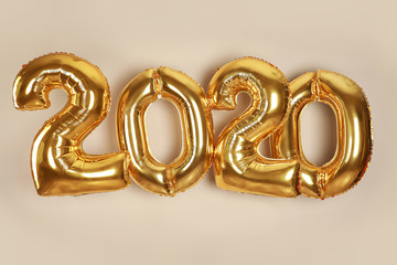 Golden balloons for party decoration on beige background. 2020 New Year celebration