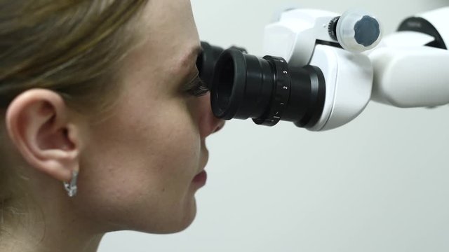 Doctor making teeth examination research survey using microscope in dentistry. Dentist is treating patient in modern dental office.