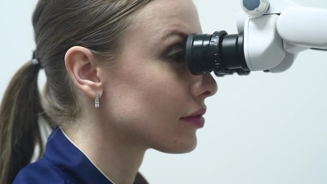 Doctor making teeth examination research survey using microscope in dentistry. Dentist is treating patient in modern dental office.