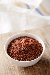 Wild red rice in a bowl on a wooden background. Natural organic raw 