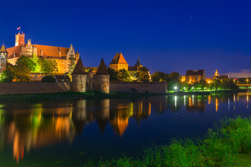 Fototapeta premium Malbork castle over the Nogat river at night, Poland