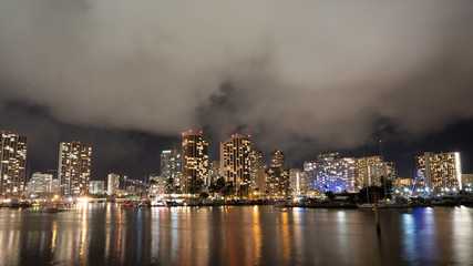 Cityscape of Honolulu at night city lights reflecting in the ocean with low lying fog