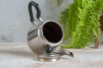 Silver metal tea pot on concrete background.