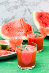 Fresh watermelon blended drink with mint leaves and a heart of watermelon in glasses on a wooden table