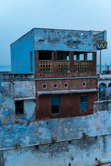 Weathered old house on dirty shore of Ganges River in Varanasi at dusk