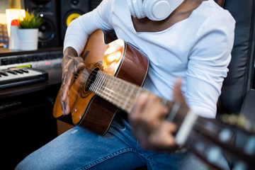 Acoustic guitar held by musician of African ethnicity during process of singing