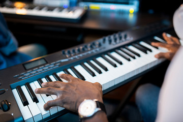Hands of young African composers or musician touching keys of pianoboard