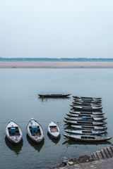 Boats floating on riverbank of Ganges River at sunsrise