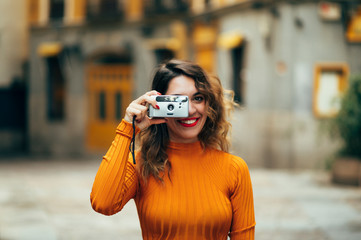 Pretty woman taking photos with camera reel in streets of Madrid