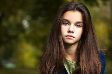 Naklejka premium Pretty brunette little girl posing in autumn park background