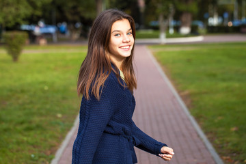 Pretty brunette little girl posing in autumn park background