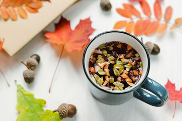Mug with hot black herbal tea on table with acorns and mixture of red leaves