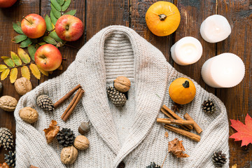 Burning candles, harvest, spices, nuts, leaves and firtree cones on warm sweater