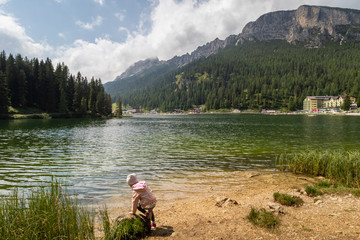 Small Child (girl) during the hiking trail in front of Landscape View of Mizurina Lake in Dolomite Alps Mountains in Cortina de Ampezzo area of italy