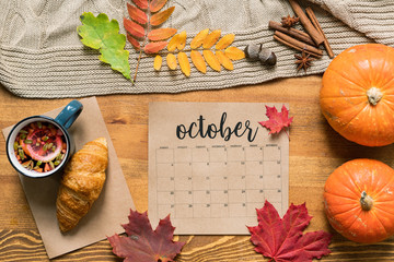 October calendar among fresh pastry with tea, ripe pumpkins, leaves and spices