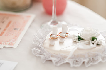 Gold wedding rings on the white rose background