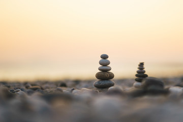 Balanced stone pyramid on pabbles beach with sunset. Zen rock, concept of balance and harmony.