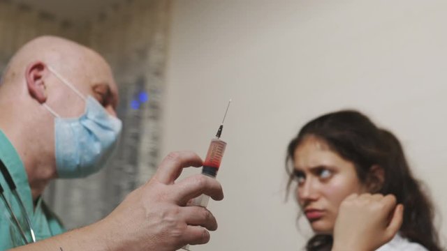 Sick caughing woman getting syringe drug injection by an experienced ambulance doctor - Needle close up and covering area with a sponge