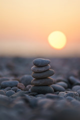 Balanced stone pyramid on pabbles beach with sunset. Zen rock, concept of balance and harmony.