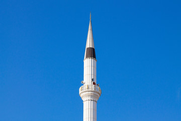 The tower of the mosque minaret against the background of the blue sky.