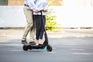 Smiling Young Couple Riding On Electric Scooter