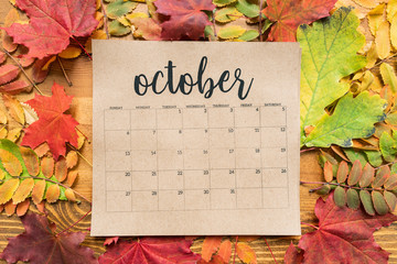 Overview of October calendar sheet and group of colorful autumn leaves