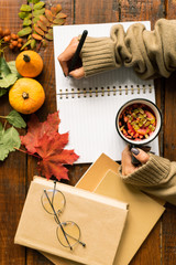 Overview of human hands with drink holding pen over blank page of copybook