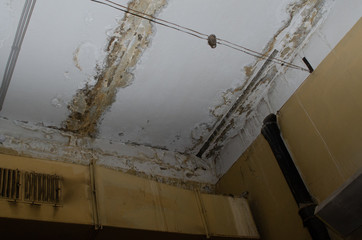 Big wet spots and cracks on the ceiling of the domestic house room after heavy rain and lot of water