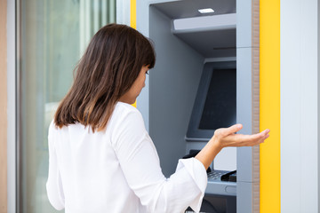 Stressed Woman Looking At Her Bank Account Balance At ATM