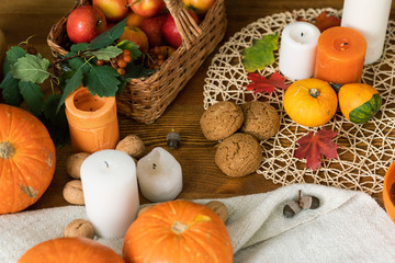 Composition of ripe pumpkins, candles, cookies, leaves and basket with apples