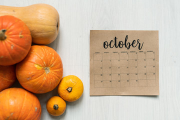 Overview of October calendar sheet and group of ripe orange and yellow pumpkins