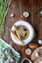 Mushroom soup with pasta with champignons and herbs on a brown wooden background