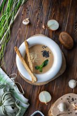 Mushroom soup with pasta with champignons and herbs on a brown wooden background