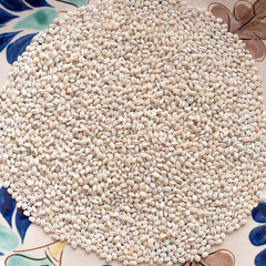 Dry pearl barley grain seed close up on colorful  bowl on table, top view
