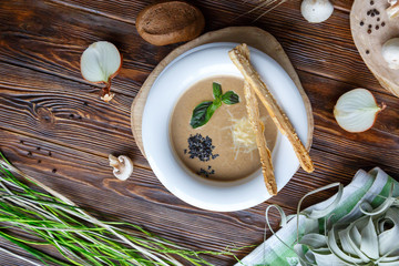 Mushroom soup with pasta with champignons and herbs on a brown wooden background