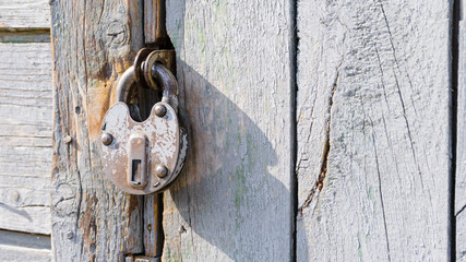 Antique padlock on a wooden door. Metal vintage lock. Rusty old door lock.