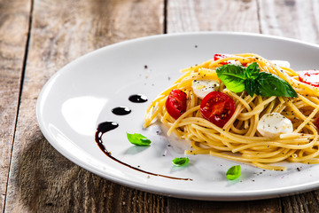 Pasta with cherry tomatoes and mozzarella cheese on wooden table