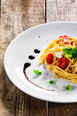 Pasta with cherry tomatoes and mozzarella cheese on wooden table