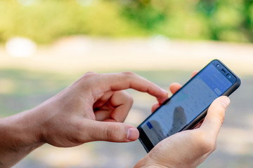young man holds a phone in his hand and writes a message or makes purchases online close up