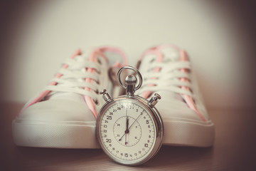 White women's sneakers, shoes for sports, close-up and stopwatch. Concept of fitness, sport, healthy lifestyle.