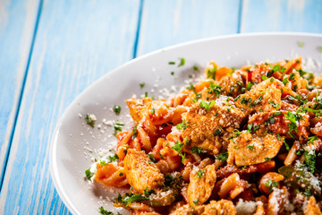 Pasta with tomato sauce and vegetables on wooden table