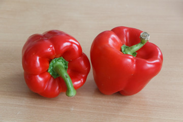 Two whole red peppers on a table