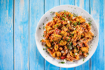 Pasta with tomato sauce and vegetables on wooden table